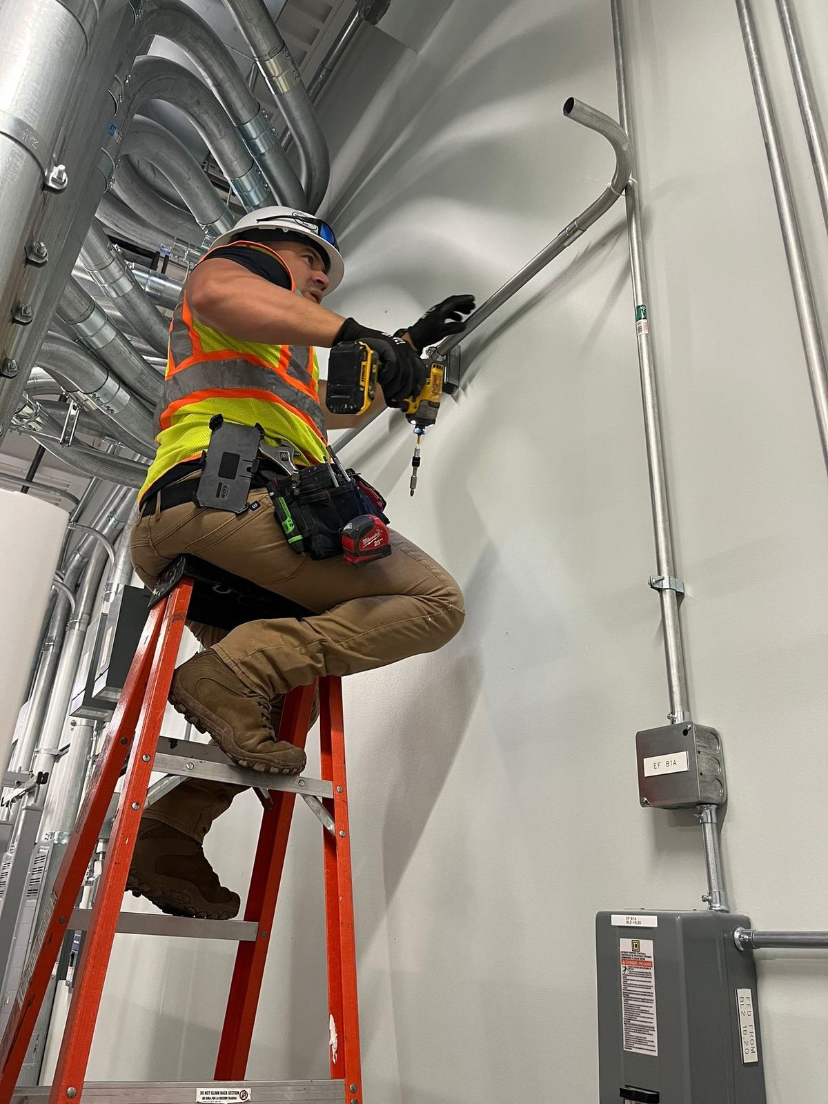 Technician installing EMT conduit and feeder on a wall